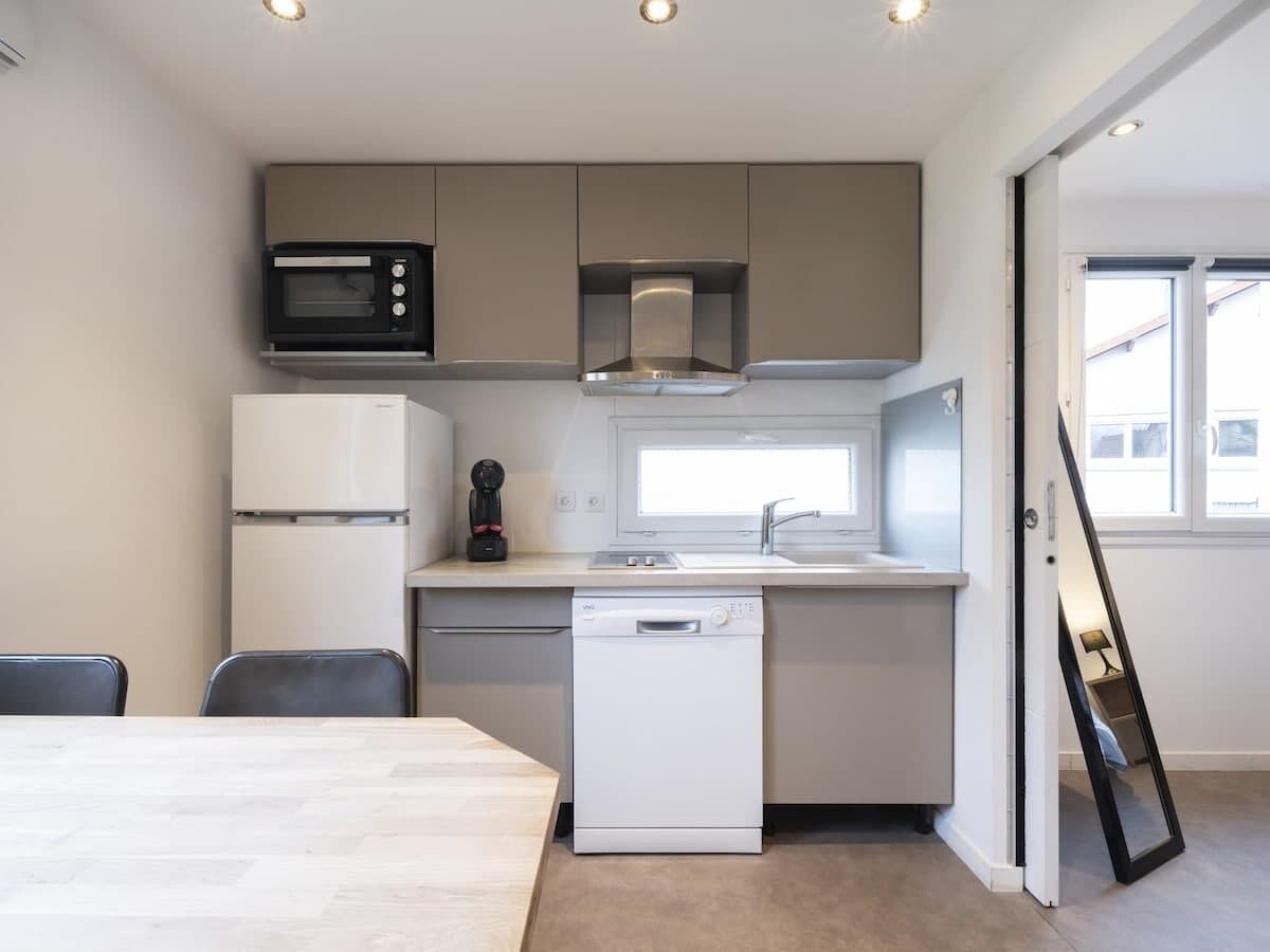 A compact kitchen with a microwave, refrigerator, dishwasher, and a window.