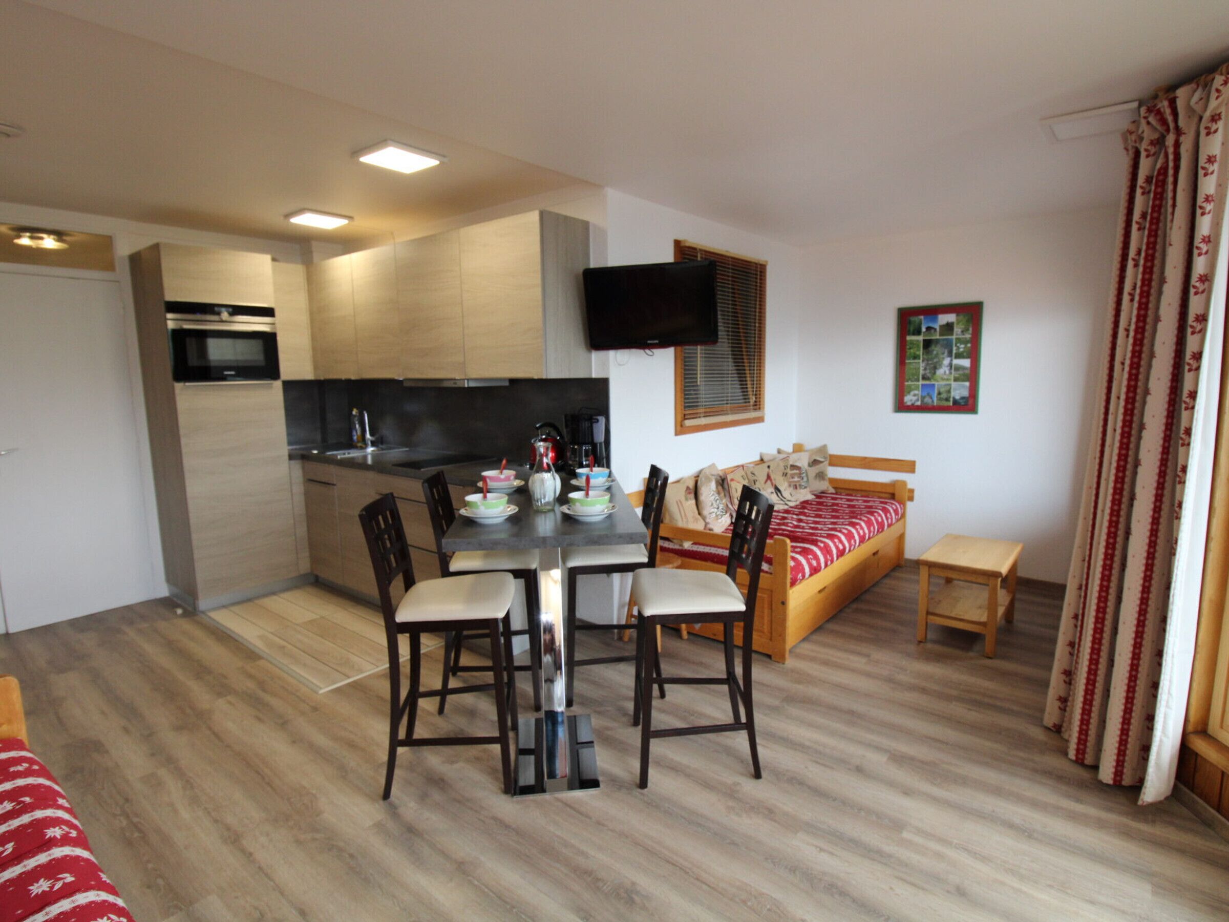 A compact living space with a kitchenette, a dining area, and a bed.