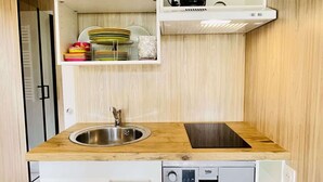 A compact kitchen with a sink, dishwasher, and a coffee maker on a shelf. - Cabane de Rafaël (Vittel)