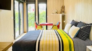 A modern bedroom with a bed, a small table, and chairs, and large windows. - Cabane de Rafaël (Vittel)