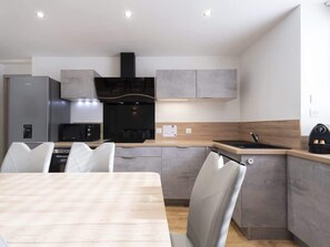 Una cocina moderna con comedor, que cuenta con horno empotrado, microondas y refrigerador de acero inoxidable.
