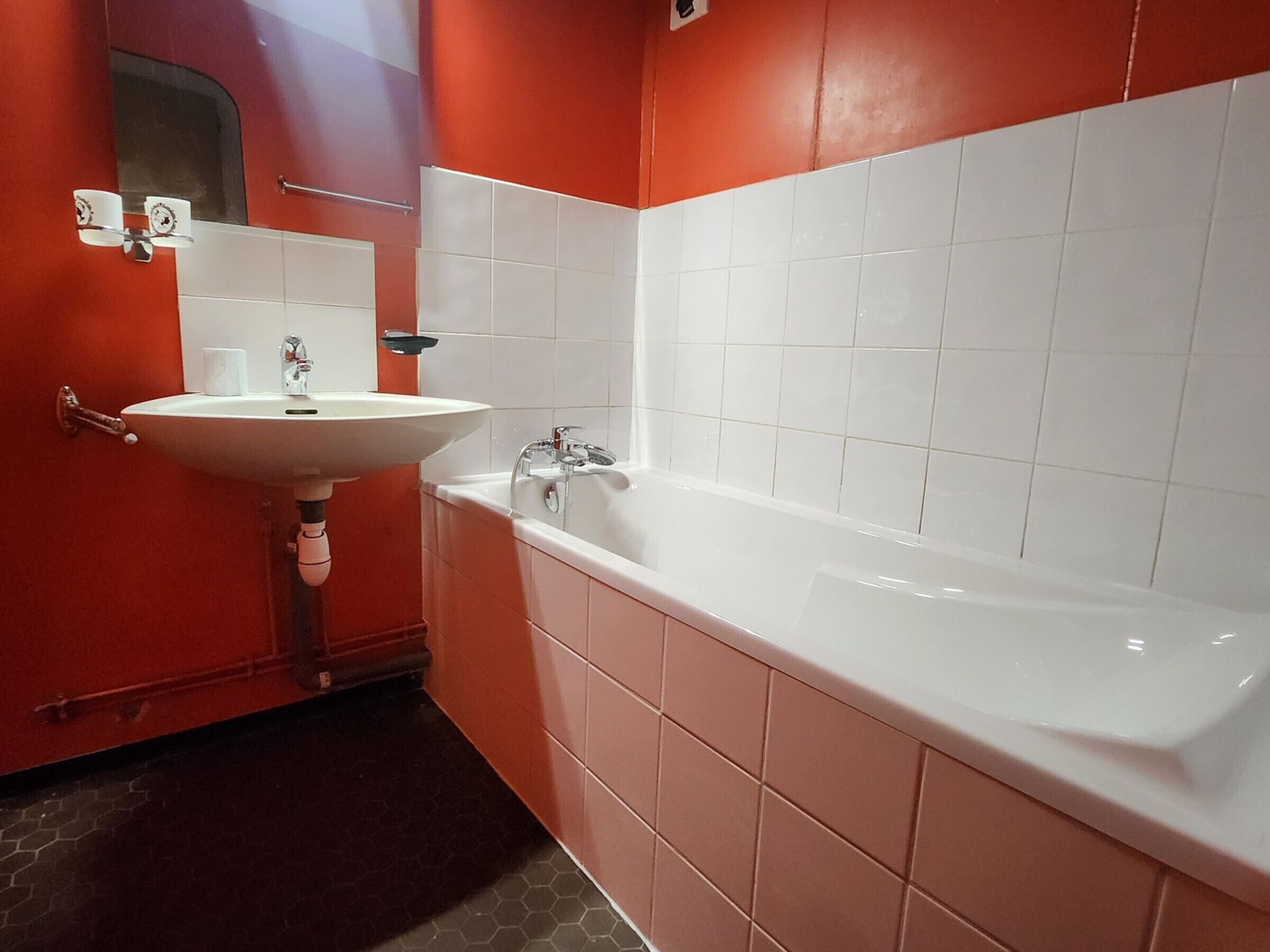 A bathroom with a white sink, a mirror, and a white bathtub.