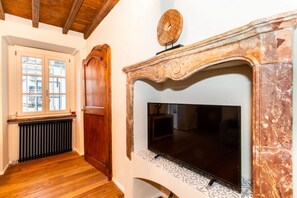 Una habitación con chimenea, televisión, puerta de madera y ventana con vista al exterior.
