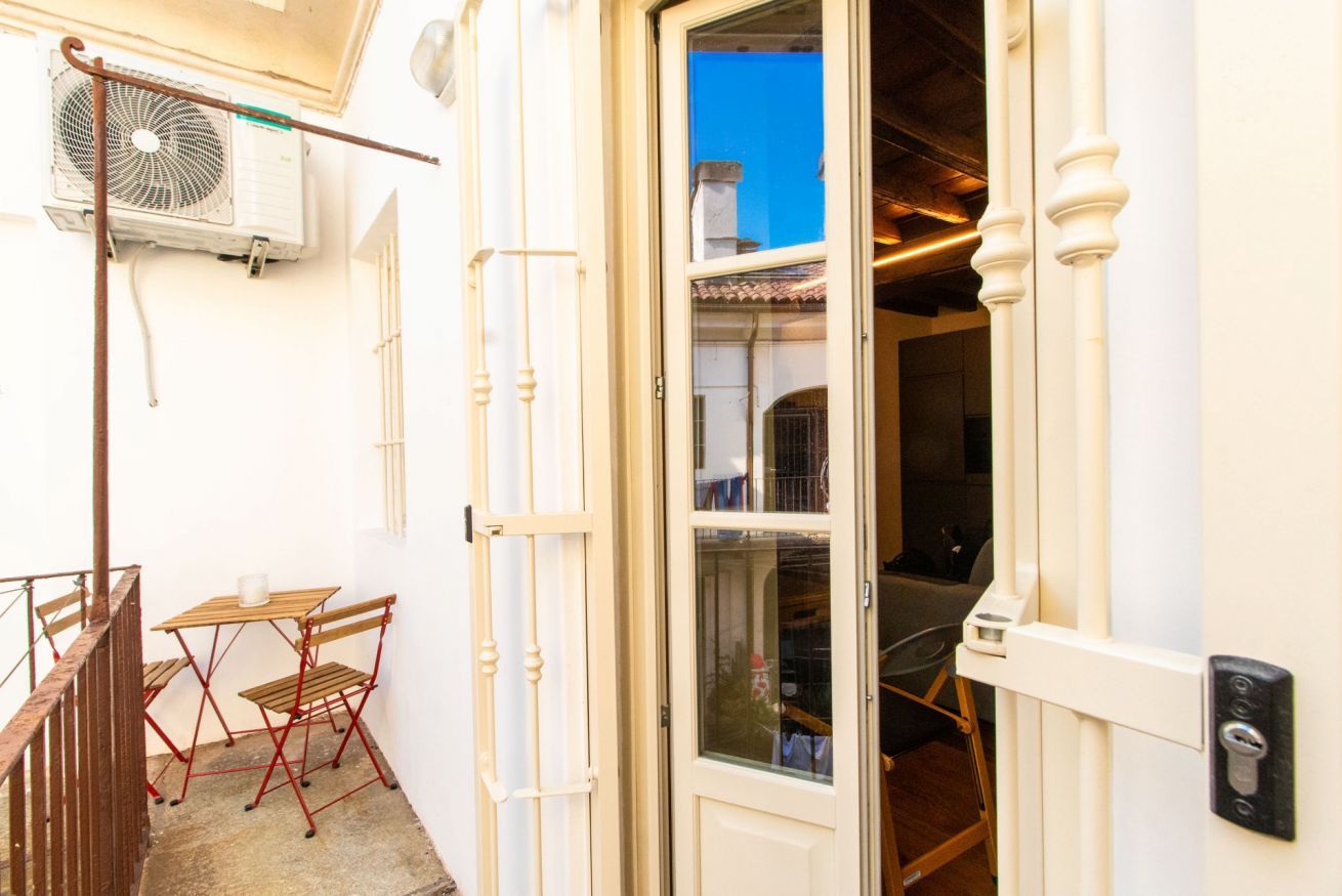 Un esterno bianco con un tavolo e sedie di legno, una porta con una finestra e un condizionatore d'aria.