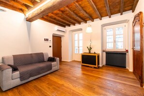 A room with a wooden ceiling, a grey sofa, a radiator, and a door. - GuestHost - Our wonderful apartment is located in the historic center of Turin, overlooking the rooftops of the Quadrilatero Romano. The house is equipped with every comfort and is perfect for 6 people. The apartment is situated very close to all the mai (Torino)