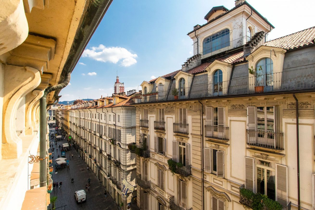 Una hilera de edificios históricos con balcones, una calle abajo y un cielo despejado.