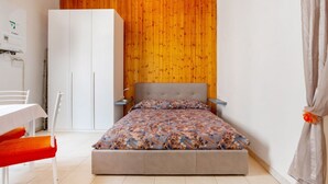 Une chambre à coucher avec un lit, une armoire, une table et une chaise.