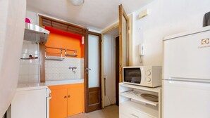 Une cuisine compacte équipée d’un four à micro-ondes, d’un réfrigérateur et d’un petit plan de travail.