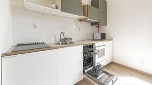 Une cuisine moderne avec des meubles blancs, un évier en acier inoxydable et un lave-vaisselle.