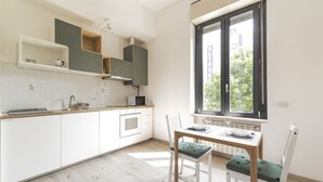 Une cuisine moderne avec des meubles blancs, un plan de travail en bois et un coin repas comprenant une table et des chaises.