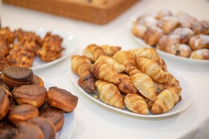 Variedad de productos de pastelería en una mesa buffet, incluyendo croissants y otros productos horneados.