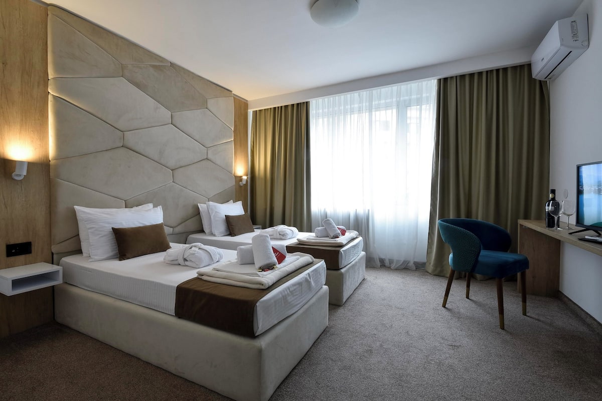 Quarto de hotel moderno com uma cama grande, uma escrivaninha e uma cadeira.
