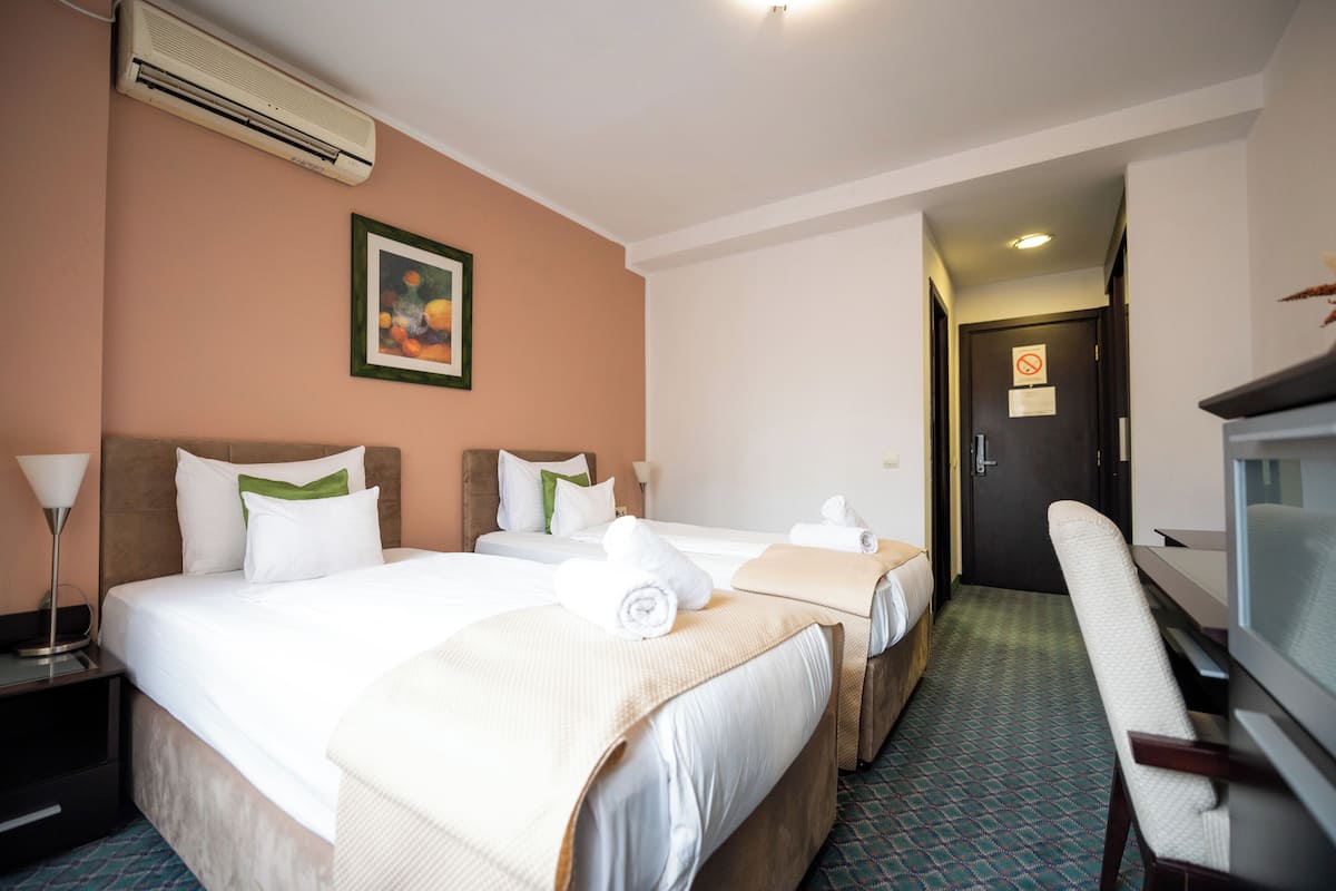 Quarto de hotel com duas camas, televisão, escrivaninha e uma cadeira.