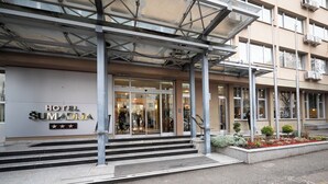 The entrance to the HOTEL SUMADJA with a glass facade, steps leading up to the entrance, and a covered area with metal beams. - Hotel Sumadija (Belgrade)