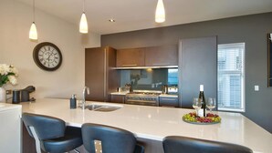 Een moderne keuken met een centraal eiland, roestvrijstalen apparatuur en hanglampen.