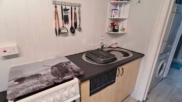 Cocina compacta con estufa, lavabo y encimera con escurreplatos.