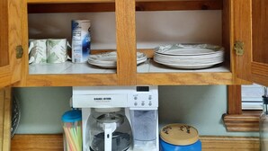 Een keuken met houten kastjes, een koffiezetapparaat en diverse keukengerei.