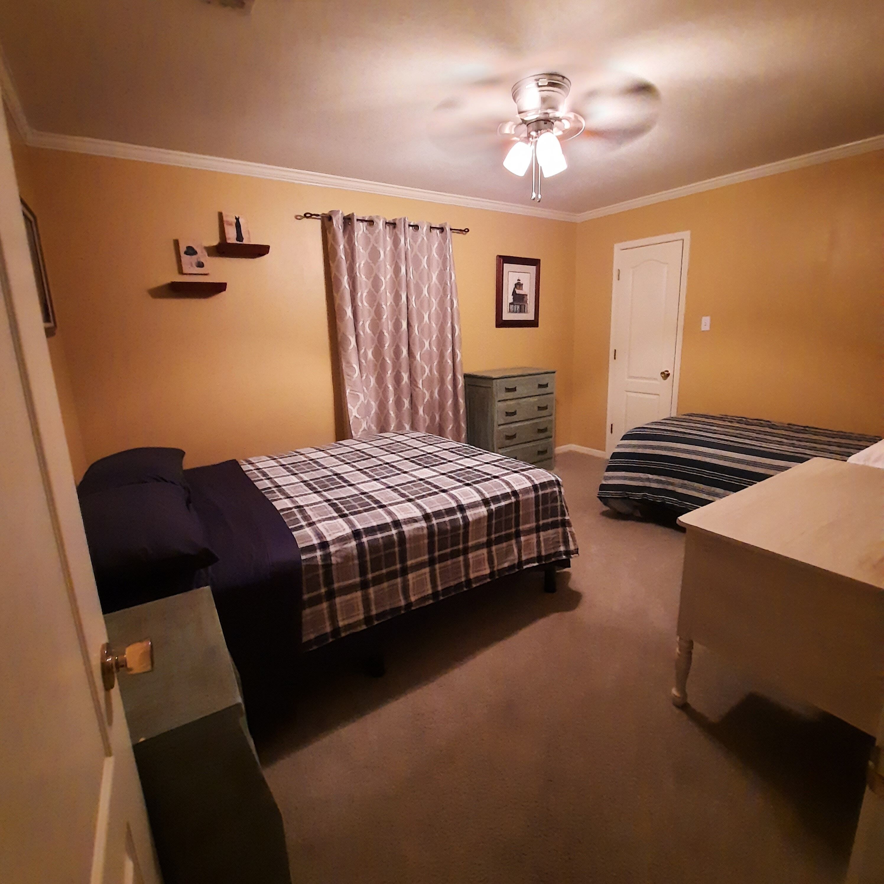 Ein Schlafzimmer mit zwei Betten, einem Deckenventilator, einer Tür und einem Schminktisch.