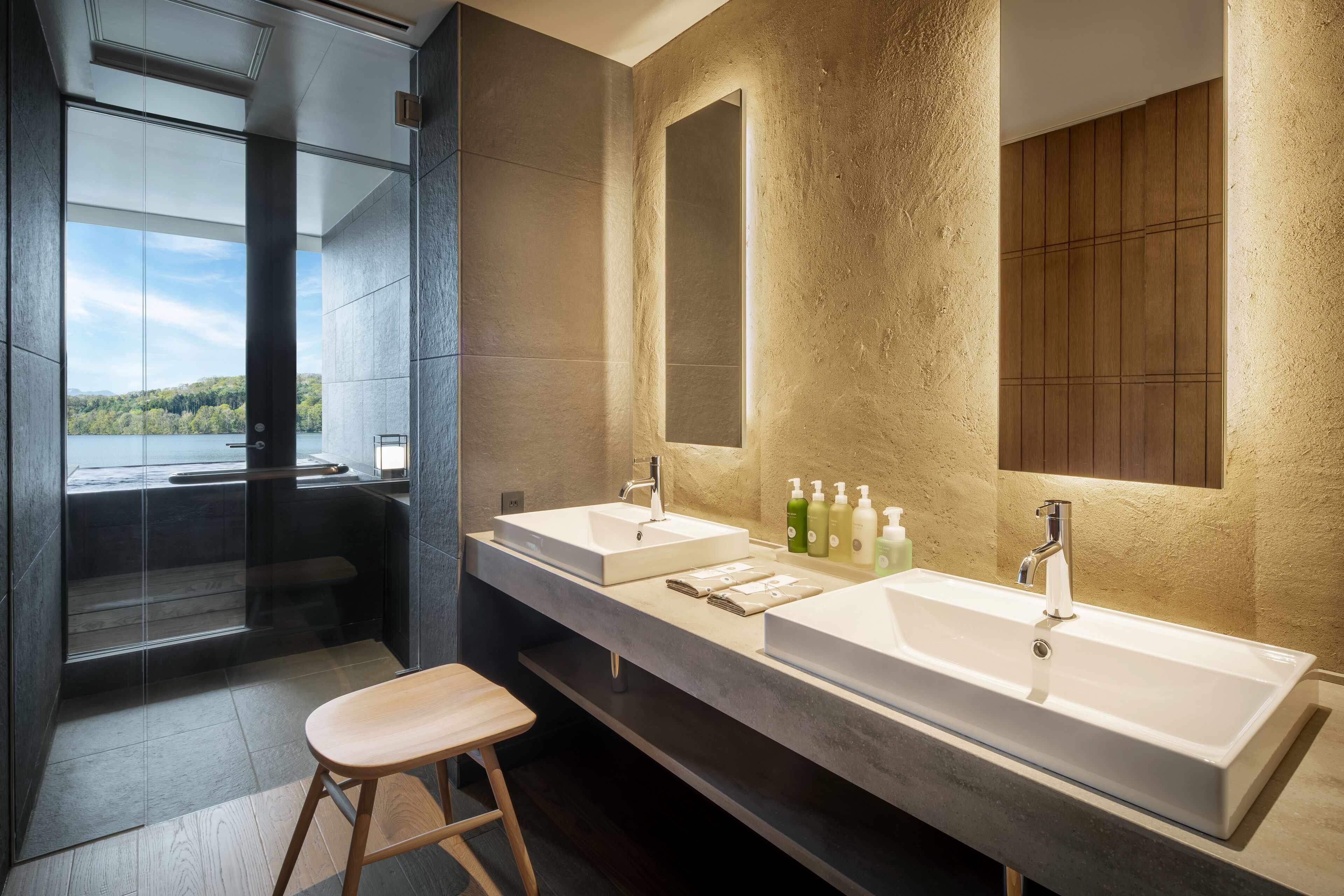 A modern bathroom with two sinks, a large mirror, and a glass shower enclosure.