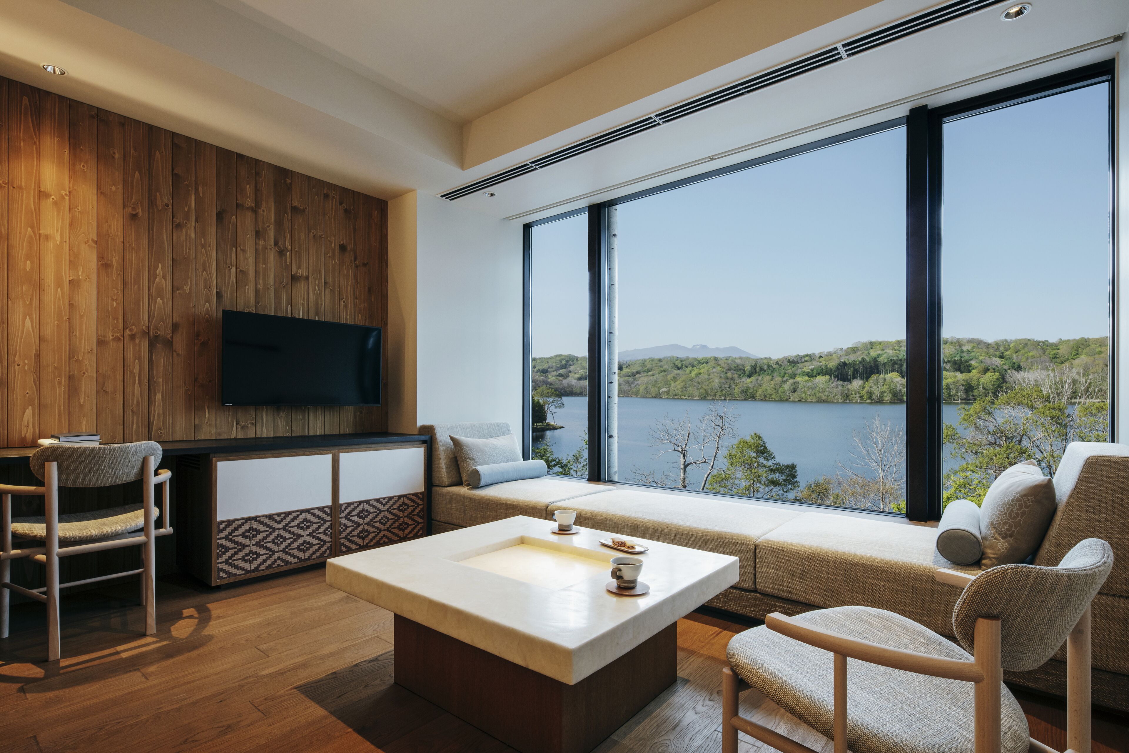 Ein modernes Wohnzimmer mit großem Fenster, Holzpaneelausstattung und einem Flachbildfernseher.