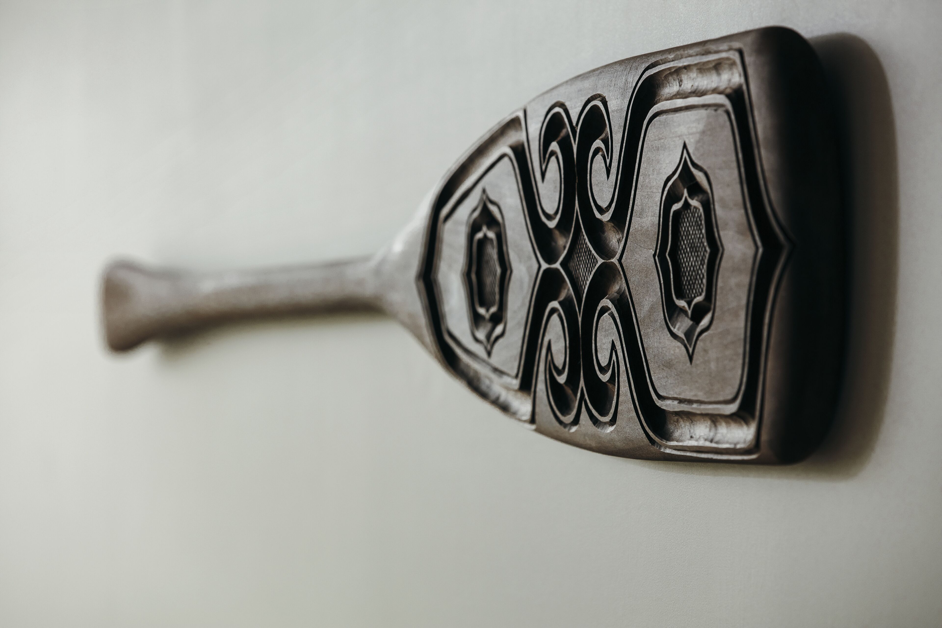 A metallic object with intricate designs, possibly a decorative item or utensil.