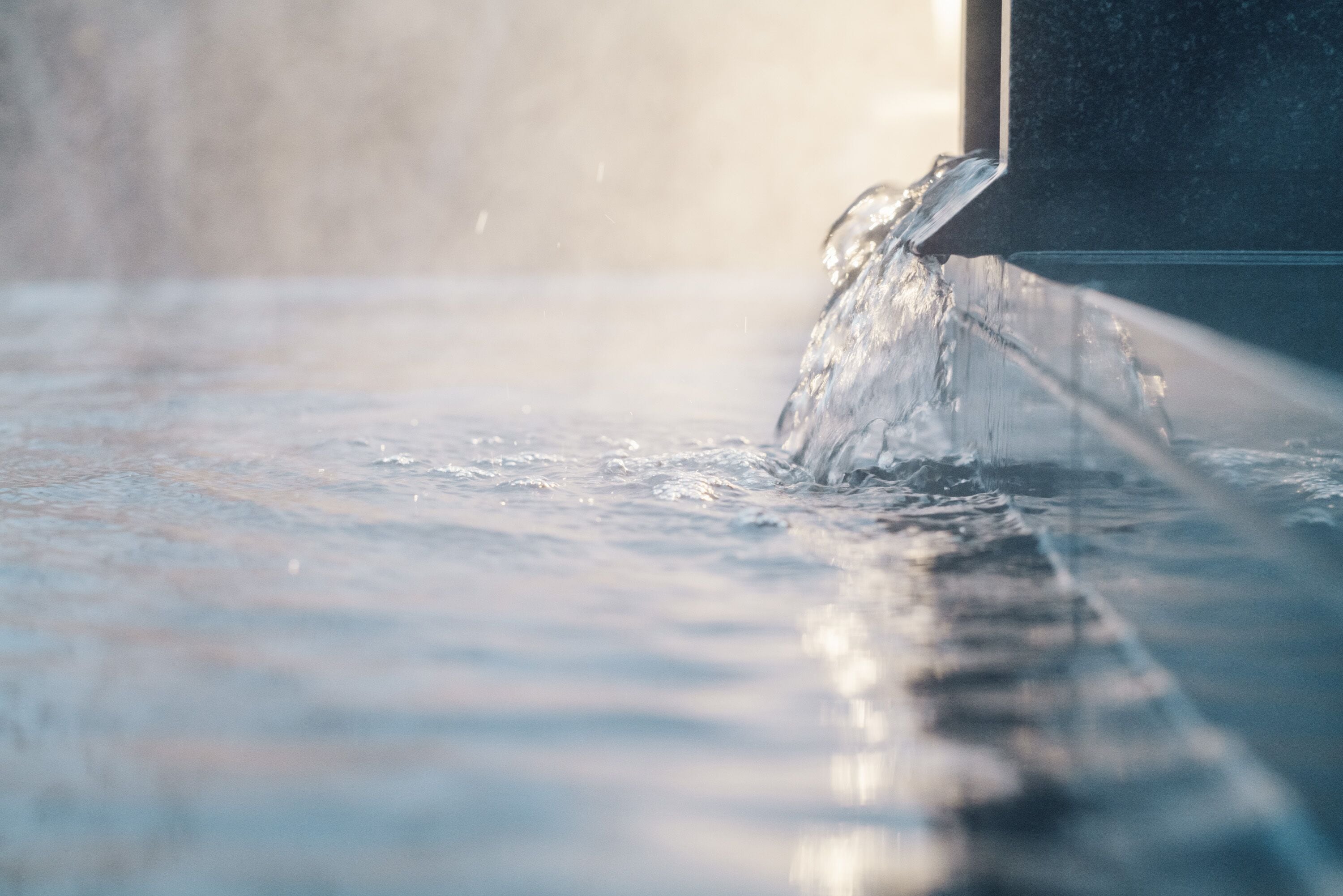 A close-up of water flowing from a faucet into a sink.