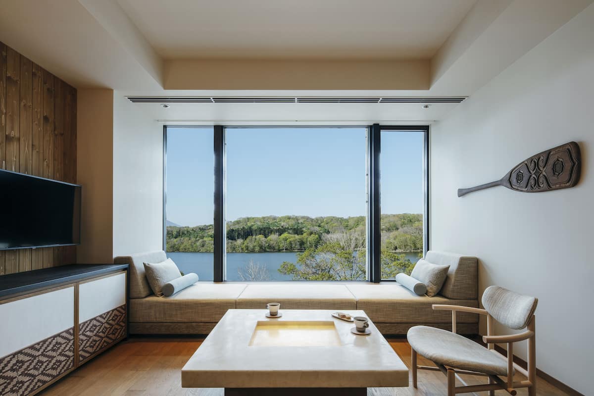 Ein modernes Wohnzimmer mit großem Fenster, Flachbildfernseher und einer Wand als Holzdekor.