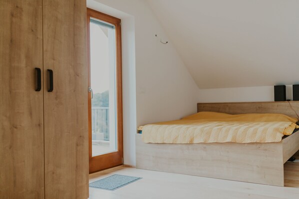 A bedroom with a wooden bed, a window, and a door.
