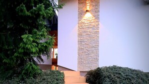 A staircase leading to a house with a stone wall and a light fixture above it. - Haloze hills in your hand (Cirkulane)