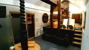 A compact, multi-level room with a spiral staircase, a small kitchen area, and a wooden bench. - Haloze hills in your hand (Cirkulane)