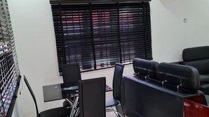A modern office space with a dining area, black leather sofas, a glass table, and a black chair. - Beautiful Suits Apartment Near Airport Lagos (Lagos)
