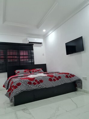 A bedroom with a bed, a TV, and an air conditioning unit. - Beautiful Suits Apartment Near Airport Lagos (Lagos)