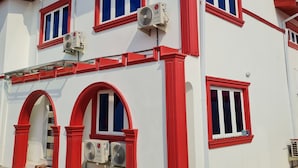 A two-story building with red-framed windows and white walls. - Beautiful Suits Apartment Near Airport Lagos (Lagos)