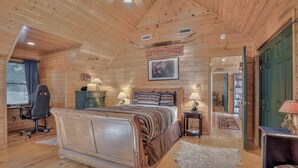 A log cabin bedroom with a large bed, a desk, and a chair. - Log Cabin, Rumbling Bald Resort Amenities - Autumn Ridge by Carolina Properties (Lake Lure)