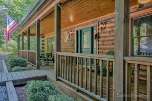 Une cabane en bois avec un porche, une porte verte et un drapeau américain.