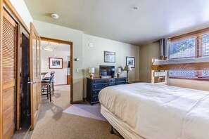 A hotel room with a bed, a desk with a chair, a dresser, and a television.