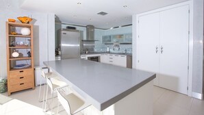 A modern kitchen with a large island, white cabinetry, and a built-in oven.