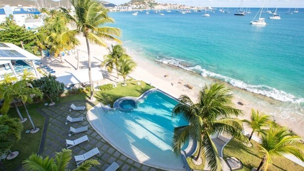 A resort with a swimming pool, beach, and ocean view.