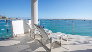 A terrace with white chairs and a table, overlooking a marina with boats.