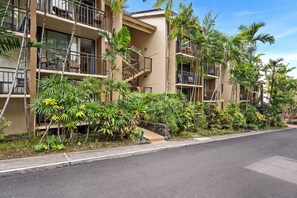 Un hotel de varios pisos con balcones, rodeado de vegetación tropical.