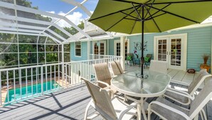 A covered patio with a glass table and chairs, a pool, and a view of the surrounding area.