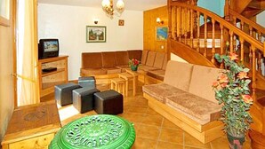 Ein Wohnzimmer mit einer Holztreppe, einem Sofa, einem Couchtisch und einem Fernseher.