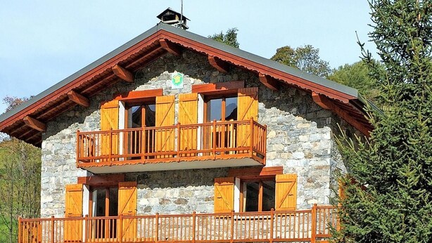 Ein zweistöckiges Steinhaus mit hölzernen Balkonen und einem Steindach.