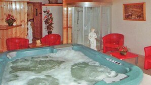 Ein Spa-Raum mit einer großen Whirlwanne, roten Stühlen und einer Statue.