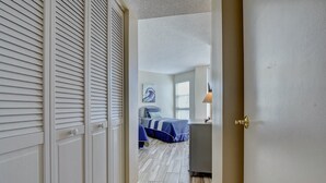 Un pasillo que da a un dormitorio con cama, mesita de noche y ventana.