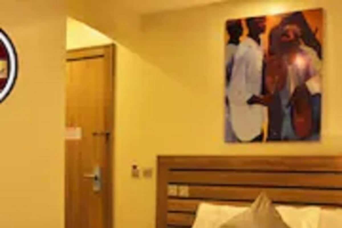 Une chambre d’hôtel avec une tête de lit en bois, un lit recouvert de draps blancs et un tableau accroché au mur.