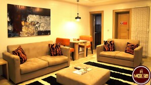 A modern living room with two sofas, a coffee table, and a painting on the wall. - Moz One Executive Guest Rooms Hombori (Abuja)