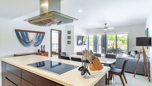 Une cuisine moderne dotée d’un îlot central, d’un coin repas avec des chaises et d’une grande fenêtre donnant sur un paysage verdoyant.