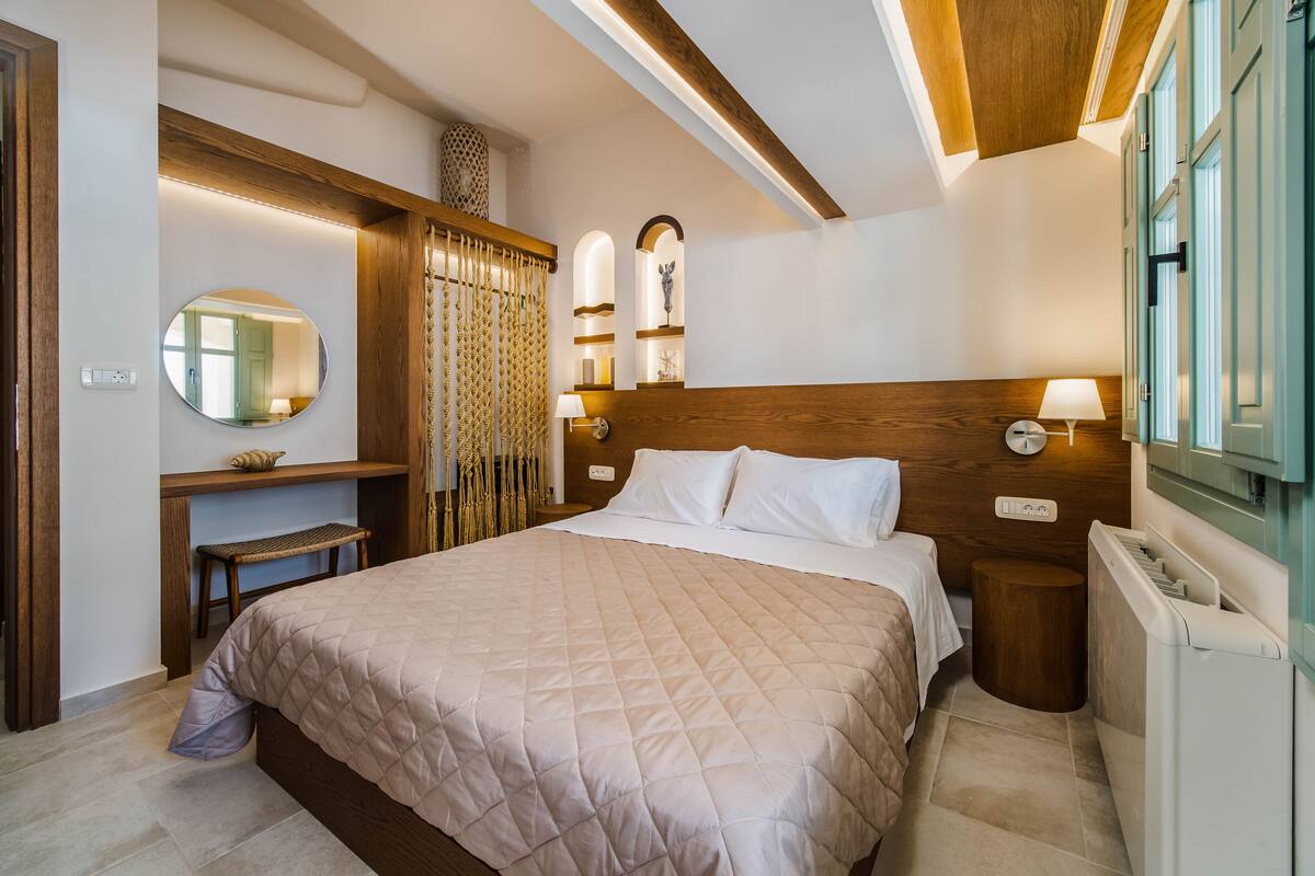Ein Schlafzimmer mit einem großen Bett, einem hölzernen Kopfteil, Nachttischlampen und einem Spiegel an der Wand.
