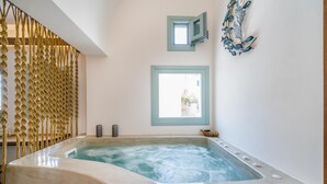 Een wellnessruimte met een whirlpool, een touwbarrière en uitzicht buiten door een raam.